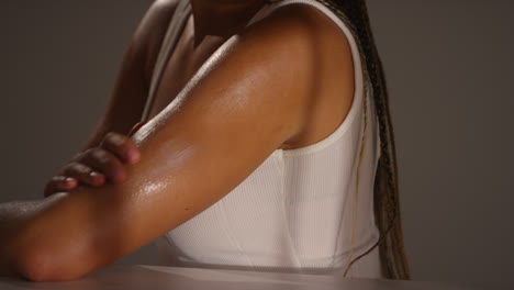 Close-Up-Studio-Skincare-Beauty-Shot-Of-Young-Woman-With-Long-Braided-Hair-Putting-Moisturiser-Onto-Arm-And-Shoulder-2